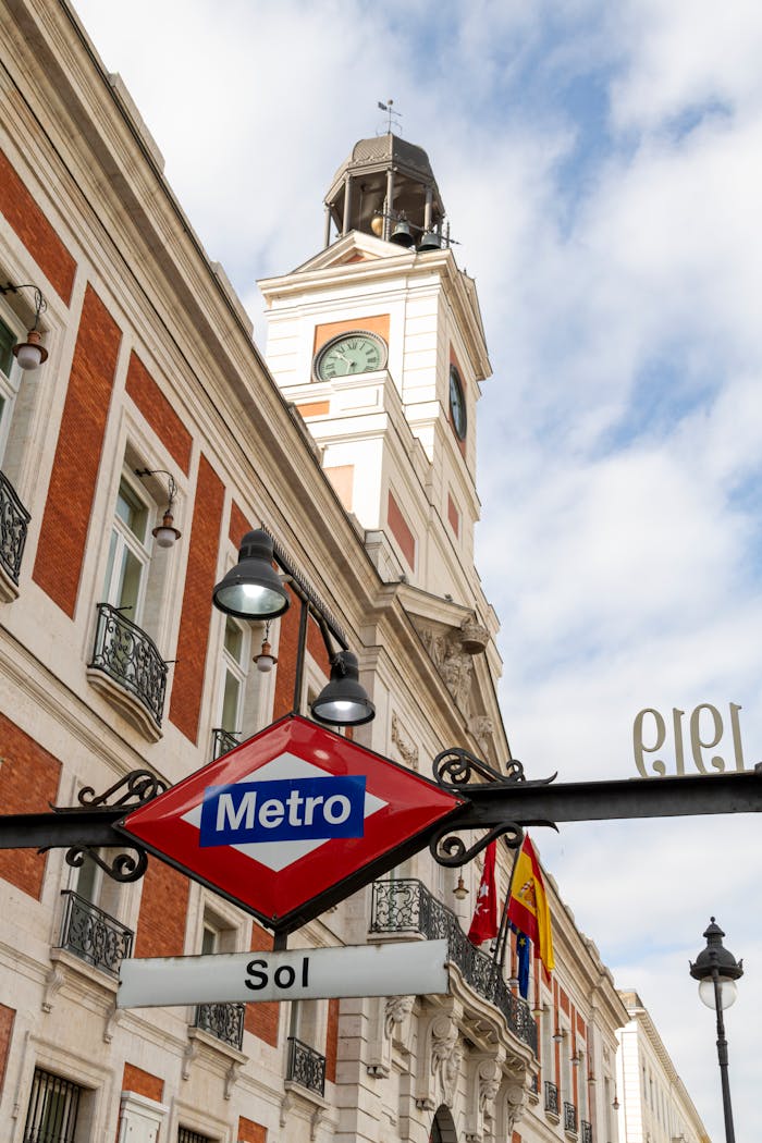View of Puerta del Sol clock tower and Madrid Metro sign in bright daylight.