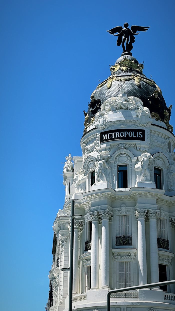 why-choose-us The iconic Metropolis Building in Madrid stands out against a vivid blue sky, showcasing its ornate architecture.